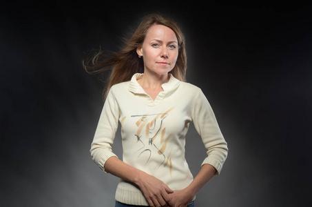 穿着米色夹克的漂亮女孩直视镜头.在摄影棚拍摄面部表情和手势照片