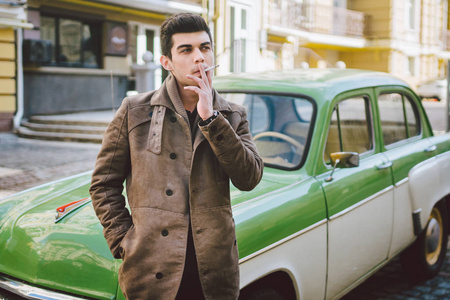 儿的肖像,深色皮肤的土耳其中东黑发女人在街上的老式汽车旁抽烟照片