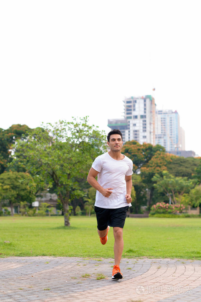 年轻英俊的西班牙裔男子在公园慢跑的全身照片