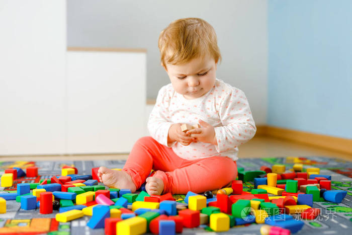 可爱的小女孩在玩益智玩具。快乐健康的孩子在家里用五颜六色的木块在家里玩耍。宝宝学习颜色和形状