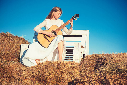 穿着白色礼服的时尚音乐家在阳光明媚的大自然中.女吉他手演奏音乐会.