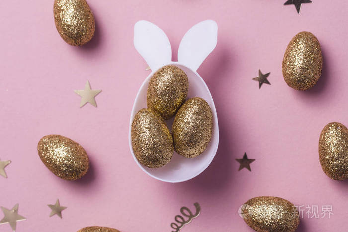 金色闪闪发光的蛋在白色复活节兔子蛋形状有耳朵