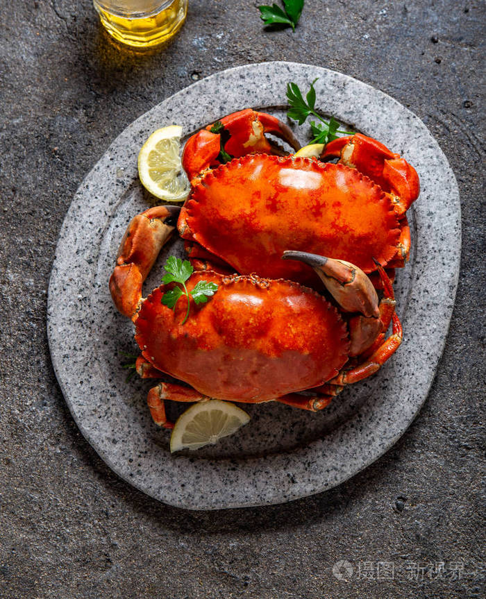 白盘子里的全熟螃蟹柠檬和啤酒灰色混凝土背景俯视图