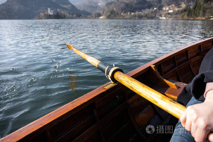 年轻女子在木船上用桨划船斯洛文尼亚湖在木船上划船