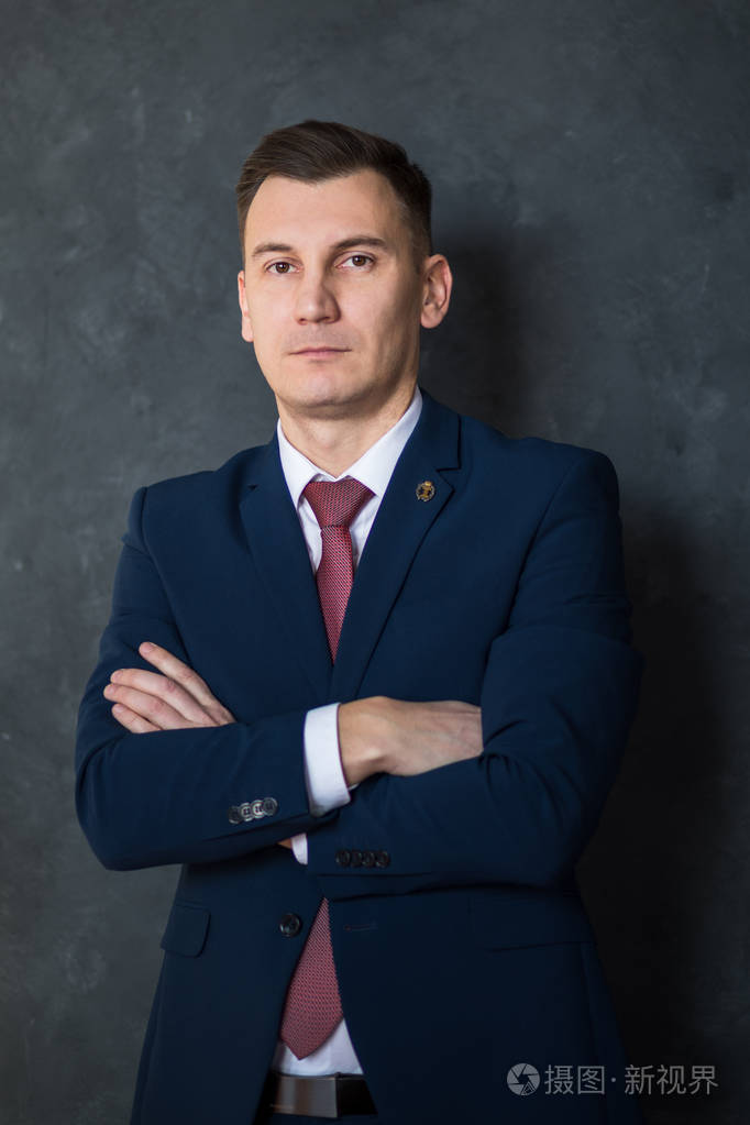 年轻聪明的律师交叉双臂站在现代办公楼的内部,成功的男性银行职员穿