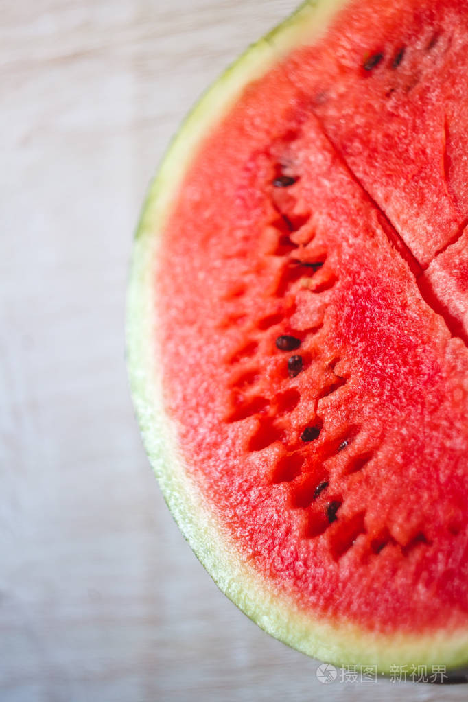 半个多汁的西瓜在浅白色的木质背景上