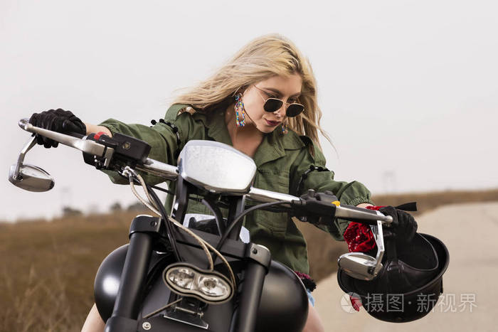 一个年轻漂亮的女人坐在一辆黑色和镀铬的摩托车上