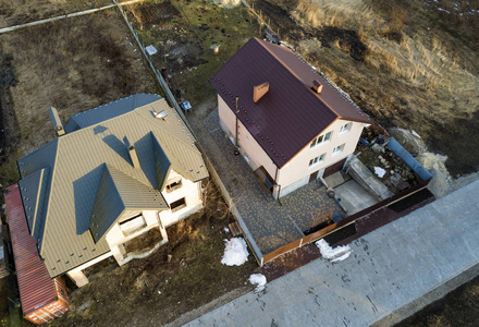 两栋新住宅的空中俯视图,屋顶为木瓦屋顶,在阳光明媚的大院子里.照片