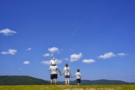 家庭价值观夏日,蓝天碧绿,绿树成荫,幸福的家庭父母和孩子们在公园里