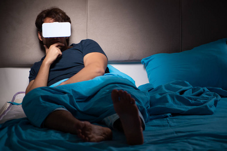 在床上玩电脑晚上在床上玩电脑游戏的年轻人照片