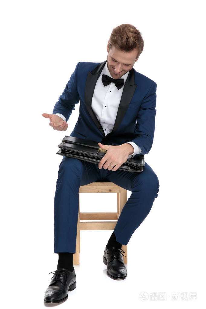 坐着的性感男人看着他放在膝盖上的公文包
