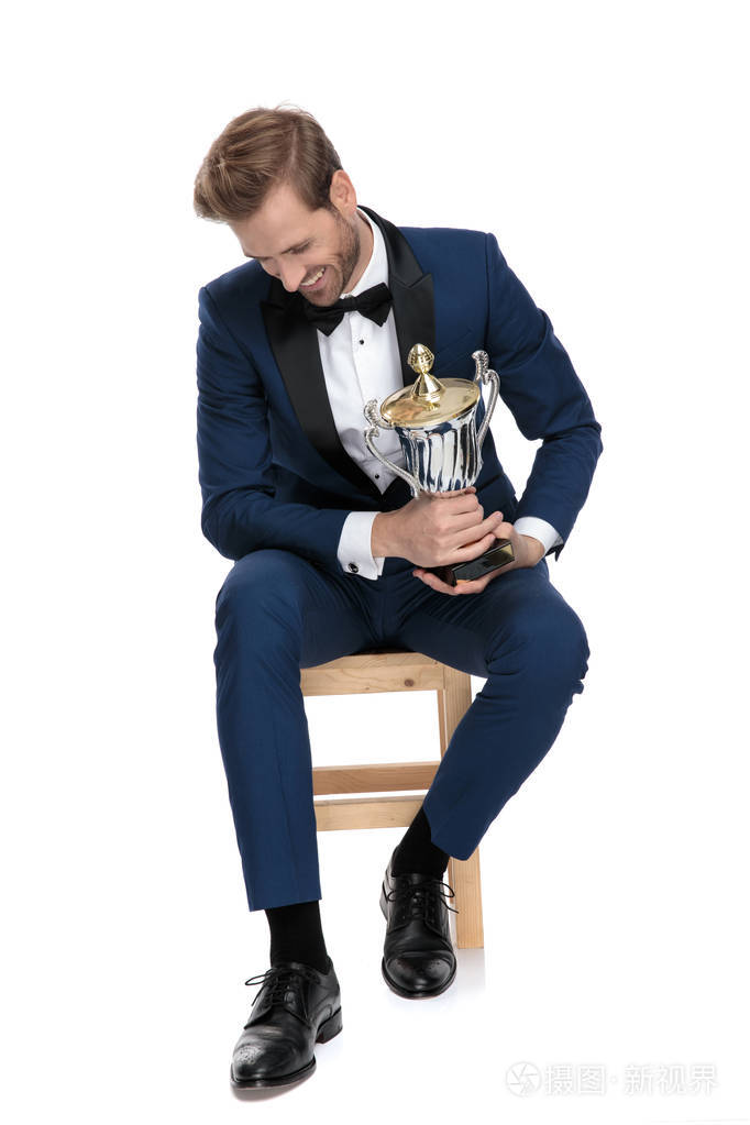 有魅力的男人低头笑着拿着奖杯
