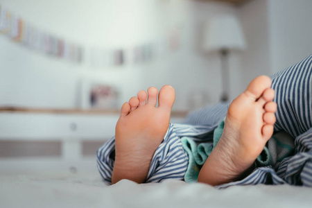 早上,一个小女孩赤脚躺在床上照片