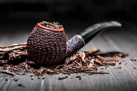 经典烟草经典的木质烟斗,烟丝堆在古董木上.照片
