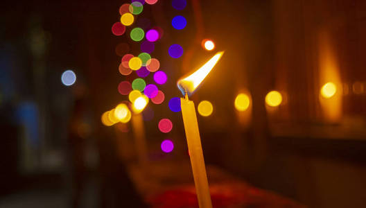 背景是微弱的彩色灯光在燃烧的蜡烛.照片