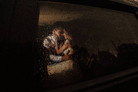 深夜爱新郎新娘深夜在车里接吻,外面正在下雨.