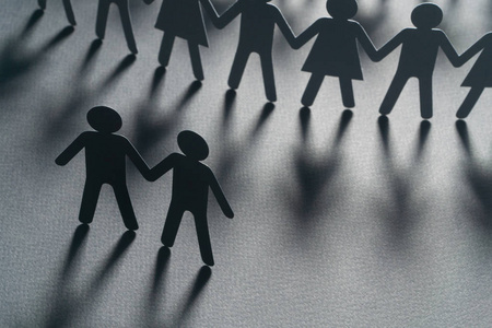 一对男性夫妇在一群纸人面前手牵手的黑色纸人在白色的表面上.