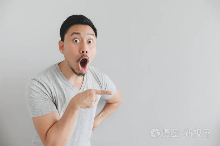 哇哦,一个穿着灰色t恤的男人惊讶的脸,手点放在空白处.