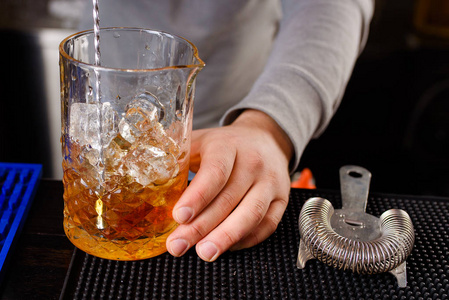 在夜总会里,一位专业的酒吧男招待正在做鸡尾酒,他手里拿着一杯鸡尾酒