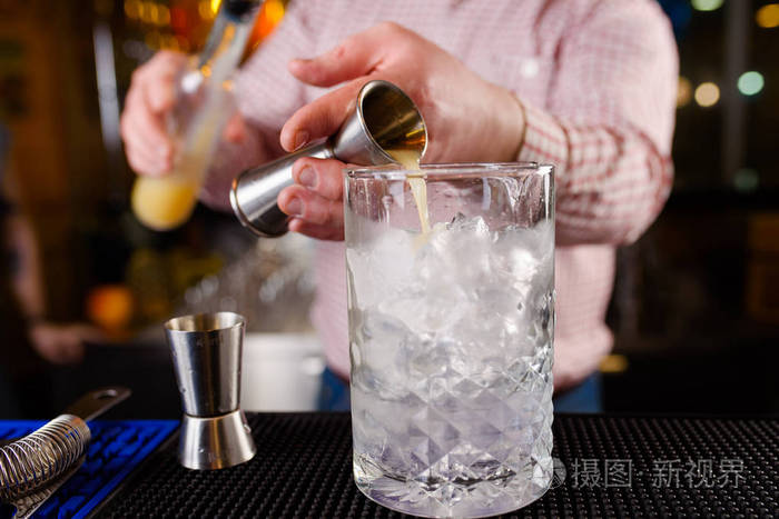 在夜总会里一位专业的酒吧男招待正在做鸡尾酒他手里拿着一杯鸡尾酒没