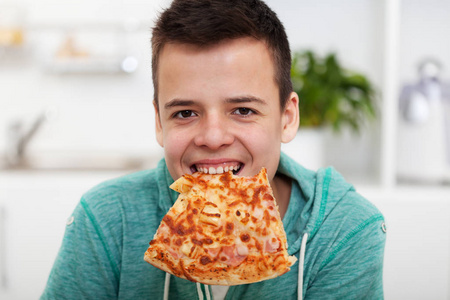 吃pizzayoung boy having fun eating a pizza - with a slice