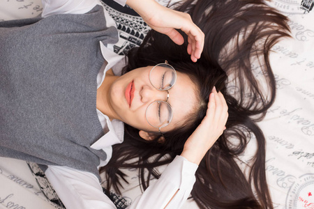 亚洲的男婴躺在哭泣眼镜女人躺在床上放松照片