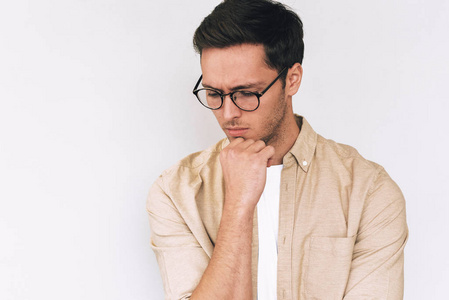 陷入思考年轻的白人男子托住下巴,陷入沉思,低头,穿着休闲装,在白色