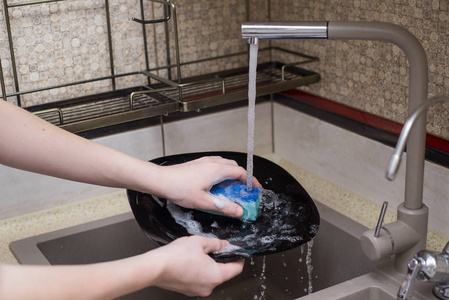 在水槽里洗碗的男孩照片