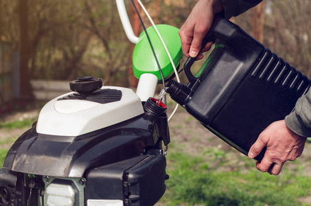 一名男子将汽油从罐中倒入耕耘机油箱照片
