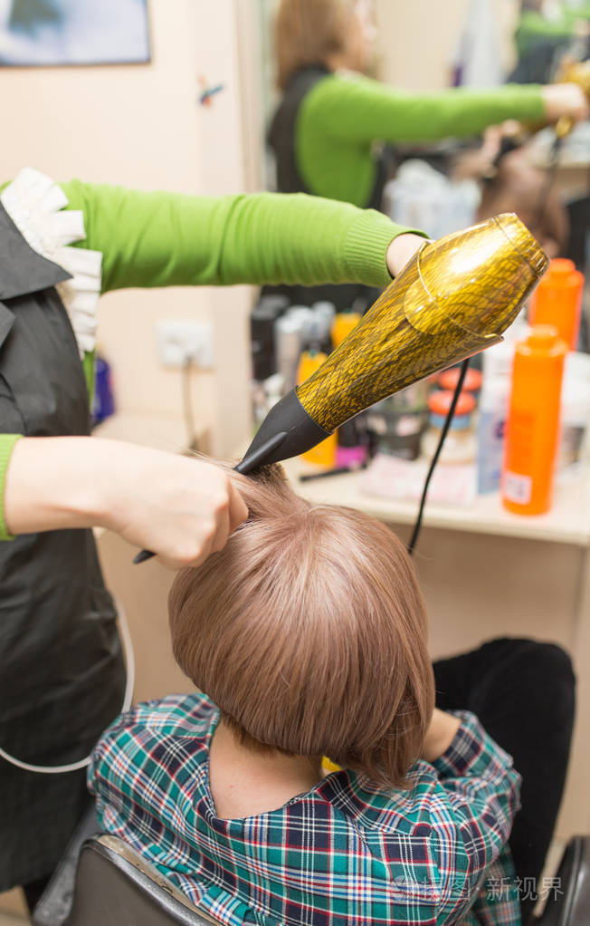 理发师用吹风机吹干金色的头发