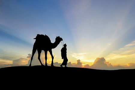 贾塔尔牵着骆驼走过印度塔尔沙漠,展示剪影照片