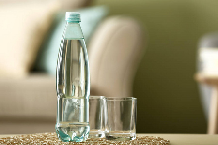 房间里桌子上放着一瓶水和玻璃杯照片