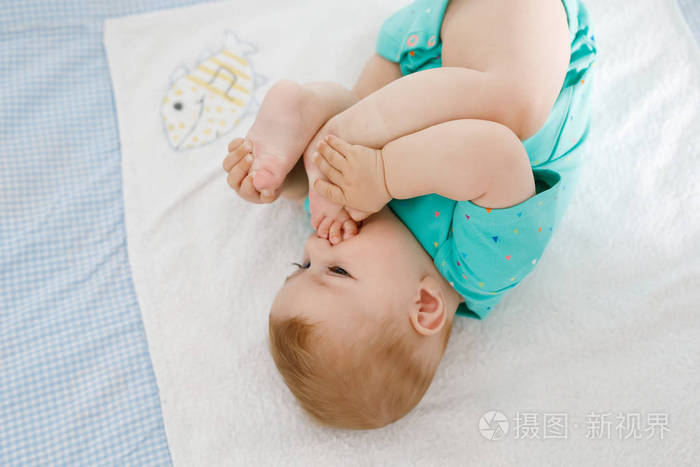 可爱的宝宝把脚放在嘴里。可爱的小女孩吮着自己的脚。健康的孩子在换衣台上。快乐的女儿。