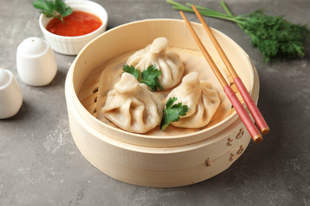 竹制蒸笼,桌上有美味的包子饺子和筷子照片