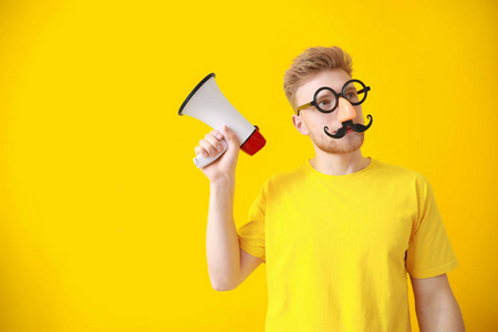 彩色背景上带扩音器的滑稽男人.愚人节恶作剧照片