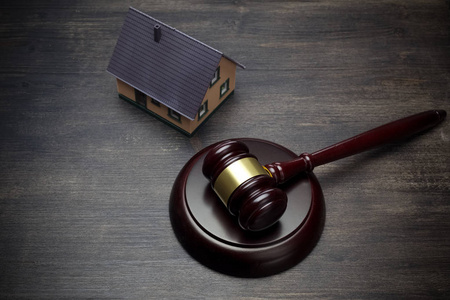 房地产拍卖.木槌和房子在深色的木质背景上照片