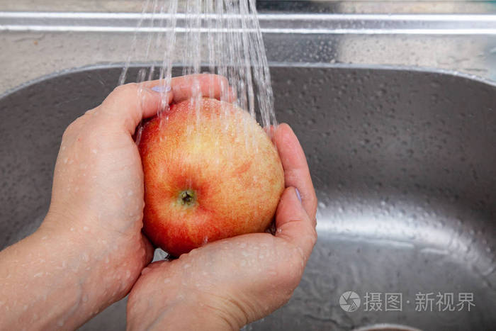 女性手洗一个红熟的苹果