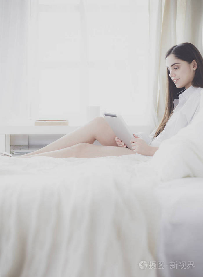 女人坐在床上看书吃早饭