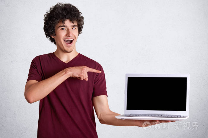 笑容可掬的高加索年轻人用前指指着笔记本电脑上的空白屏幕,穿着白色