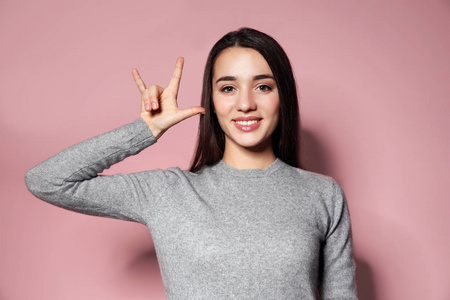 在彩色背景上用手语表达我爱你的女人照片