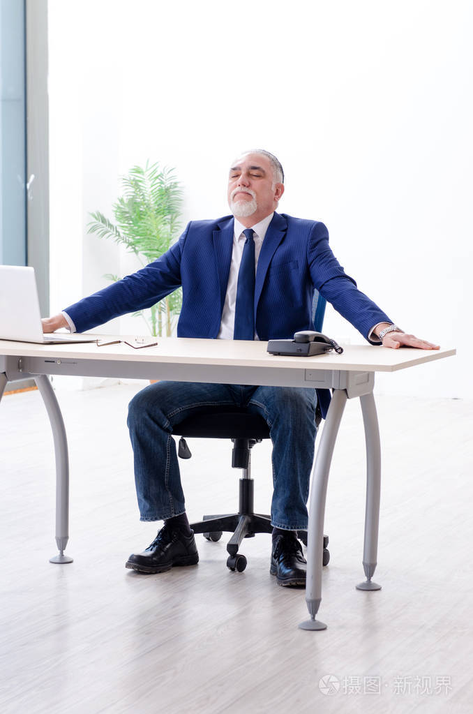 Aged businessman doing yoga exercises in the  