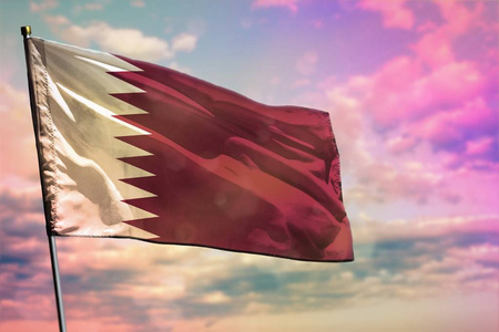 飘扬的国旗彩色多云的天空背景上飘扬的卡塔尔国旗.繁荣理念.照片
