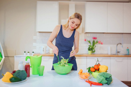 素食主义美丽的金发女人在厨房里做美味的沙拉.素食.健康饮食.