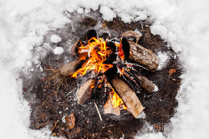 在寒冷的冬天篝火熊熊燃烧.雪,森林和火.冬天.旅游业.雪上的火焰.