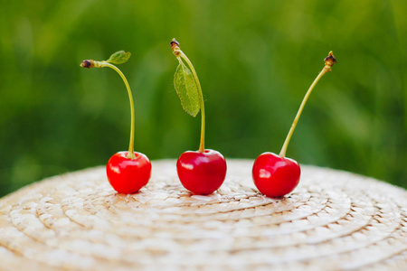 几颗成熟的甜樱桃果实,戴着草帽,躺在户外的草地上.