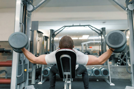 肌肉发达的年轻人在训练馆练习杠铃重物.