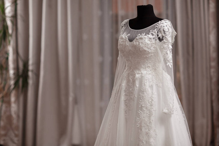 经典蕾丝丝绸婚纱挂在酒店木屋的衣架上.早上准备婚礼概念.照片