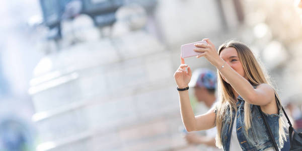 举着照相机有智能手机的青少年快乐的跨国女孩们好奇地看着手机多摄像