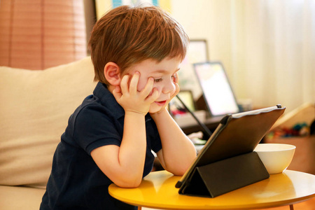 孩子在家里在床上用平板电脑.