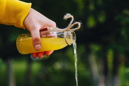 环境食物在户外的自然环境中,一只雄性手从一个瓶子里倒出自制的柠檬